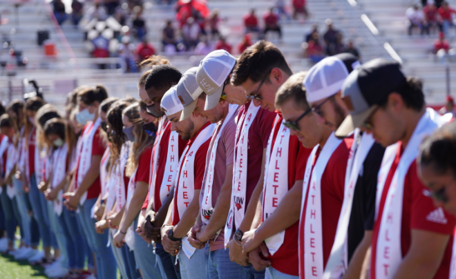 Student-athletes bow heads as they receive a blessing from the Sisters