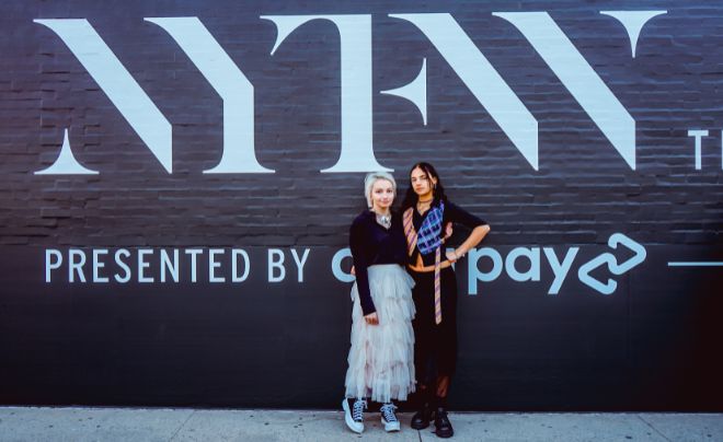 Sarah Cox and Maya Kanawati in front of NYFW sign