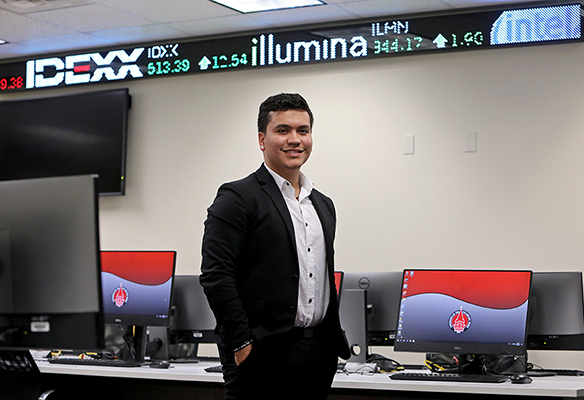 Student standing in front of stock ticker