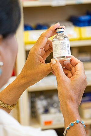 Close up of a woman holding a bottle of medicine to inspect it.