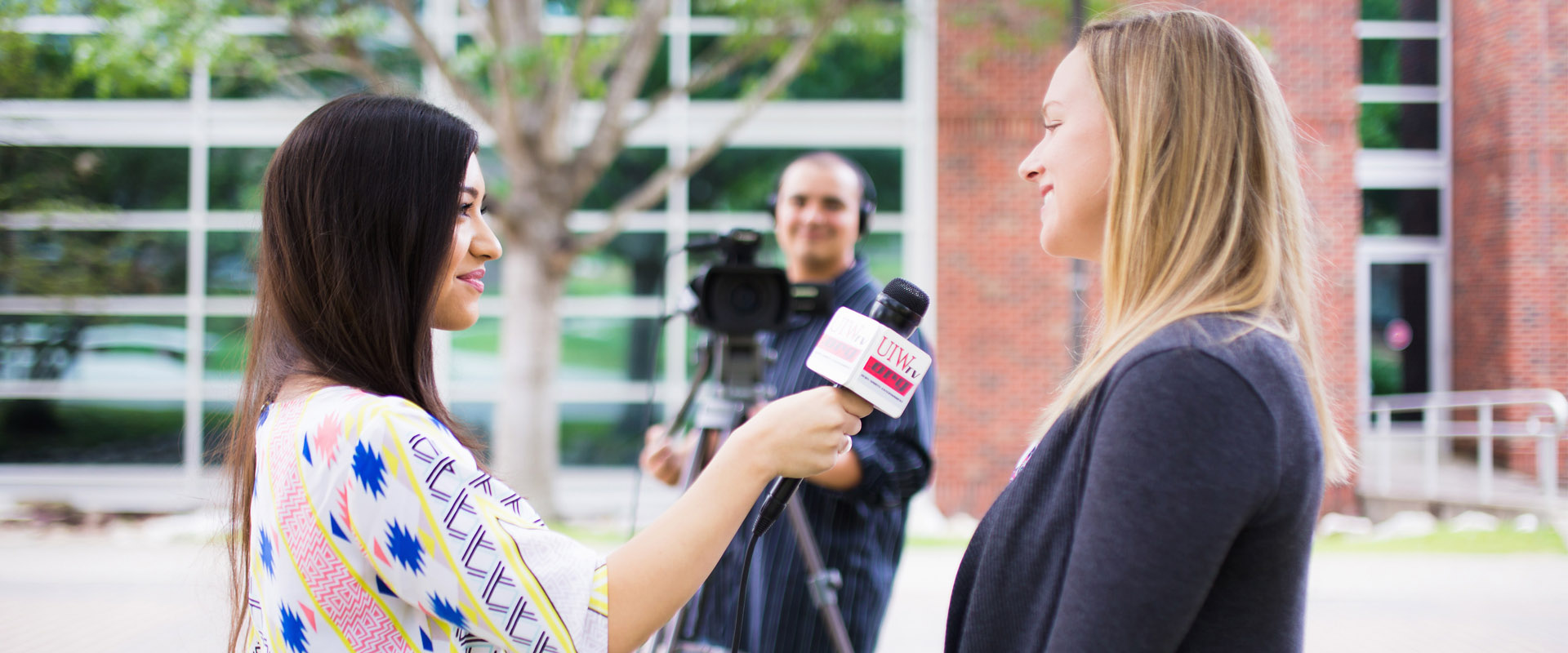 Male student filming on the back, while a female student interviews another female student for UIWtv