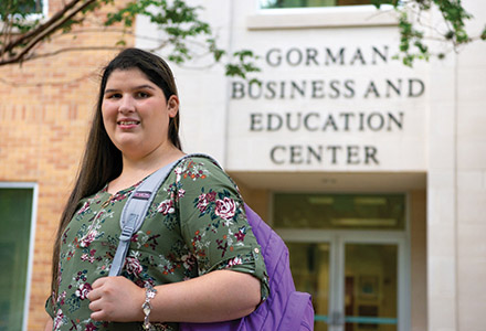 UIW Student smiling infront of Dreeben School of Education Building