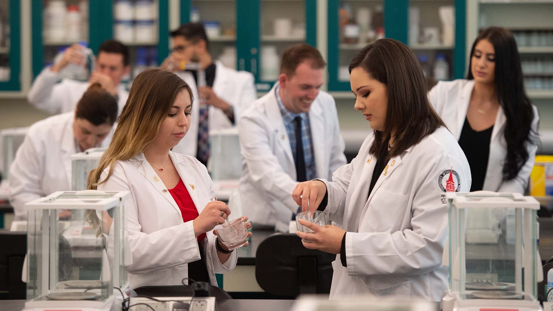 Diverse group of three students in white coats in UIW classroom