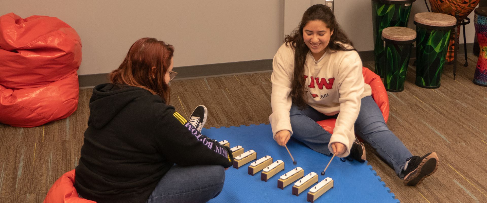 Students in a music therapy class holding various instruments sitting in a circle on the floor