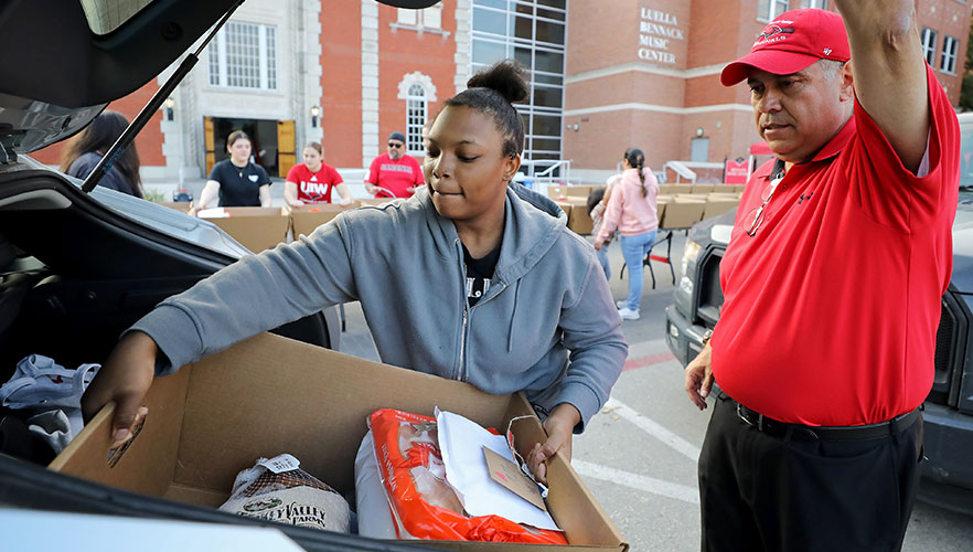 Volunteer putting Blessing Box in car with Dr. Gonzales