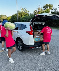 student carrying watermelon to car