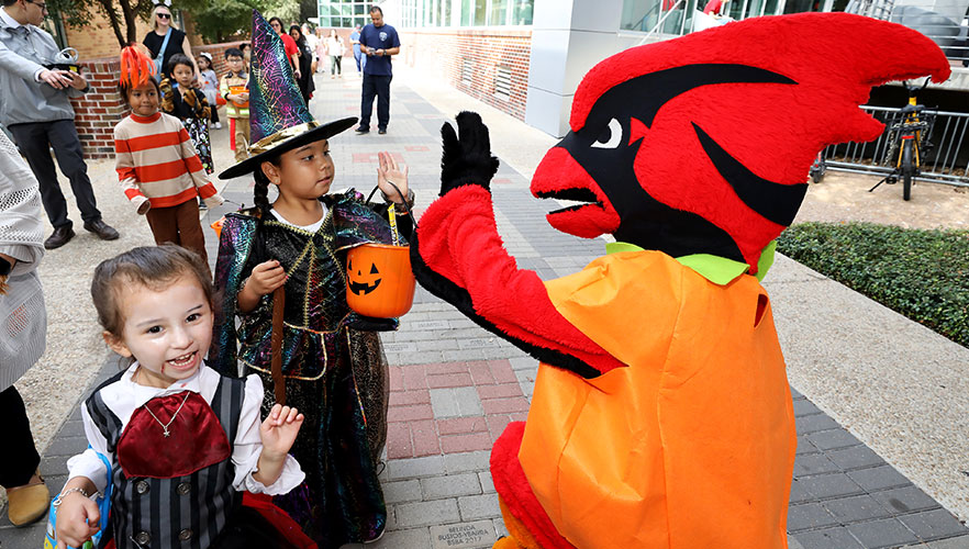 Red the Cardinal high-fiving trick-or-treater