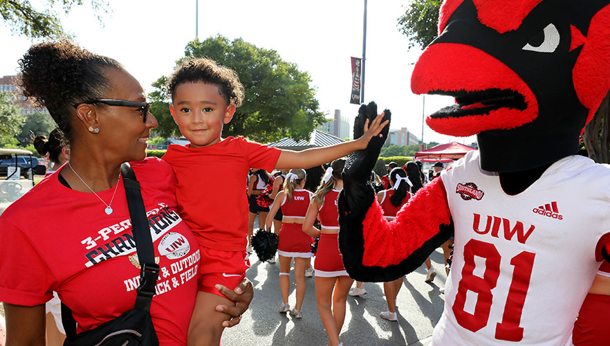 Kid high fiving Red the Cardinal