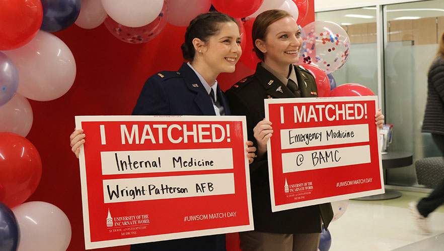 Students smiling with match signs