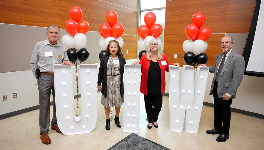 Honorees smiling in front of UIW letters