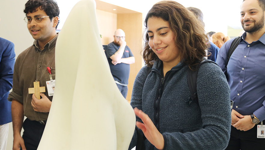 student touching sculpture