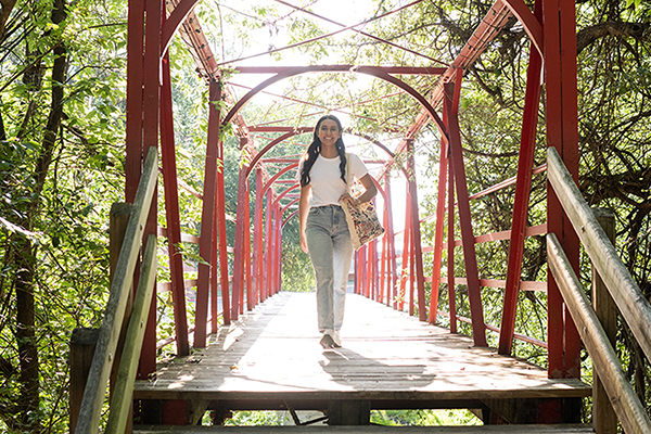 UIW student crossing a red bridge