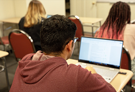 student in classroom with laptop