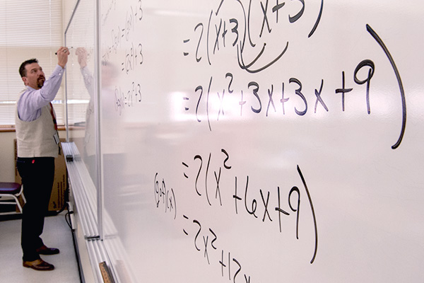 Mathematics professor working on equations on whiteboard