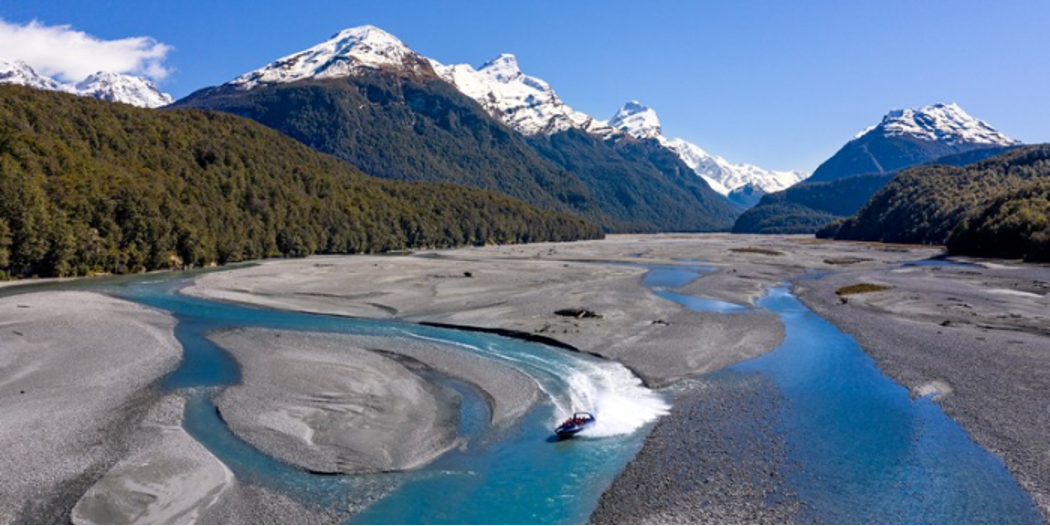 watery, dark sand in front of snow-capped mountains